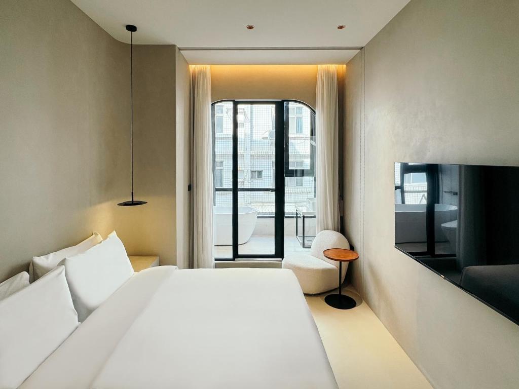 a bedroom with a large white bed and a window at Hope Hotel Tainan - Kangle Branch in Tainan