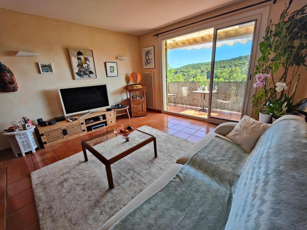 un salon avec un canapé et une télévision dans l'établissement Beau duplex au calme en pleine nature avec piscine, à Mougins