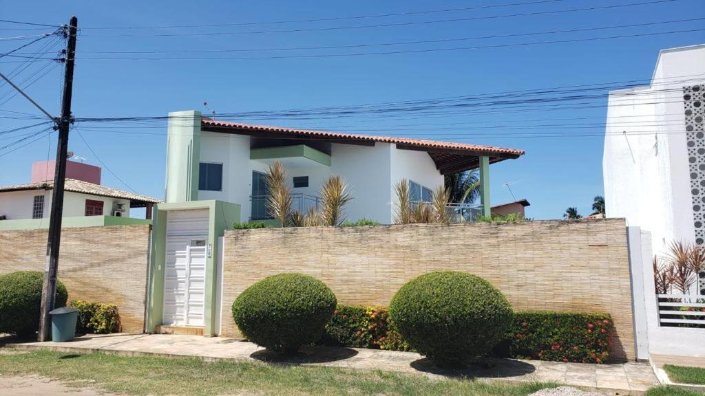 a house with a brick wall and bushes at Sonho de Verão in Paripueira