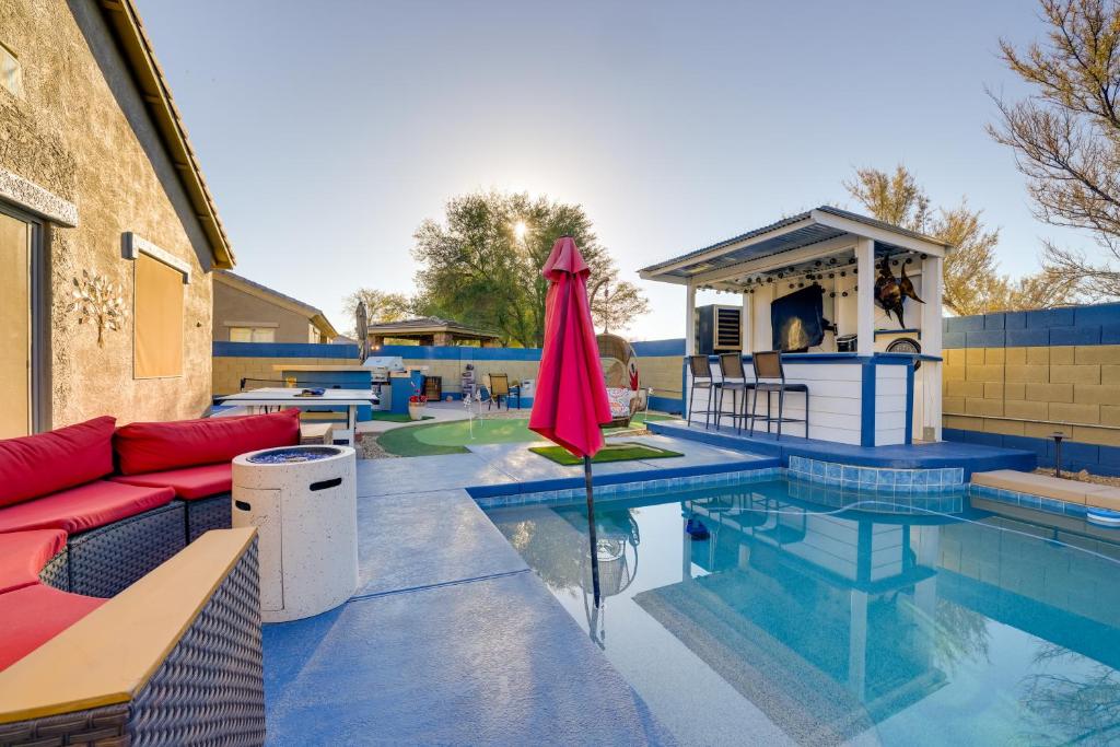 ein Pool mit einem roten Regenschirm neben einem Gebäude in der Unterkunft Putting Green and Hot Tub Goodyear Retreat! in Goodyear