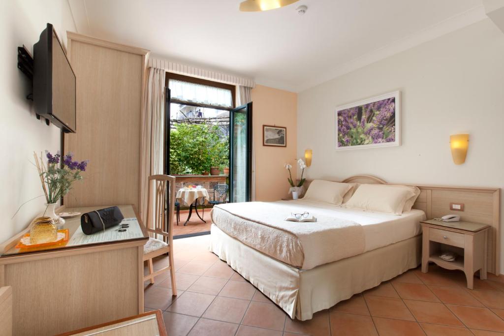 Dormitorio con cama, escritorio y TV en Relais Villa Angiolina, en Sorrento