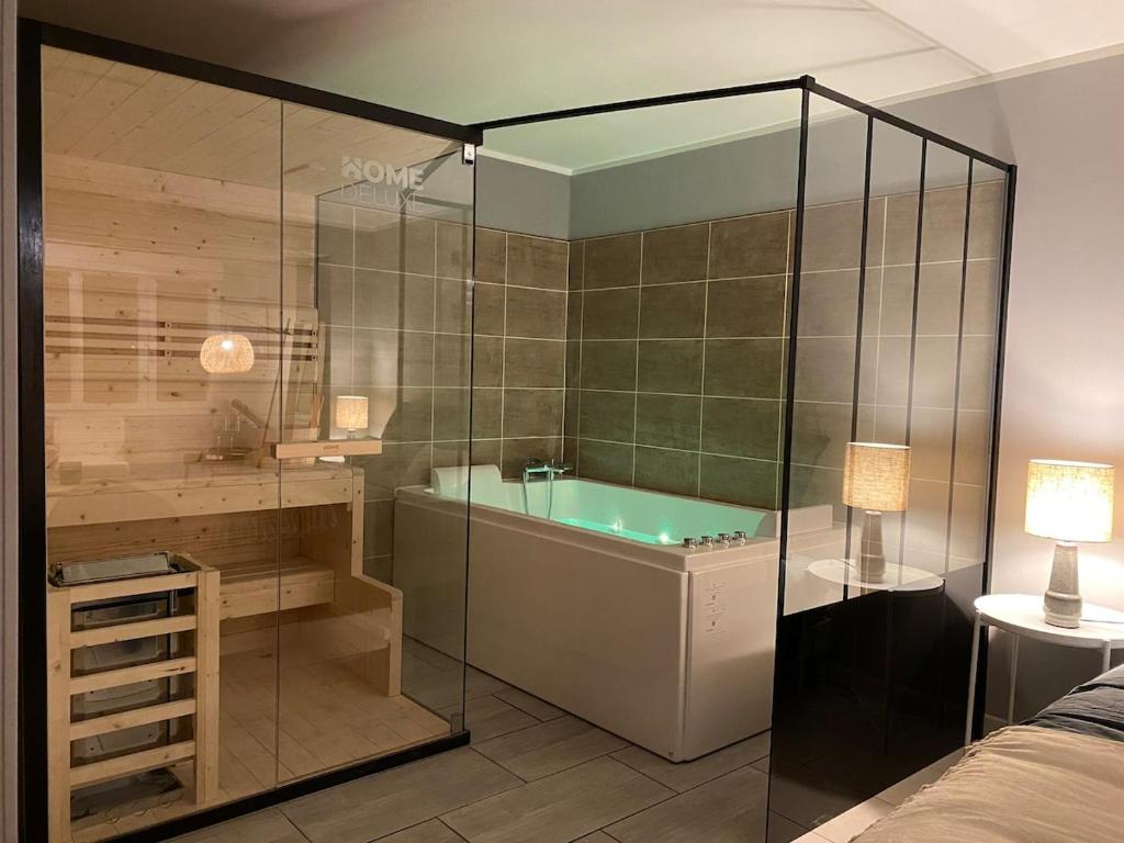 a bathroom with a tub and a glass wall at Le Nid à Bulles Scandinave in Vernon