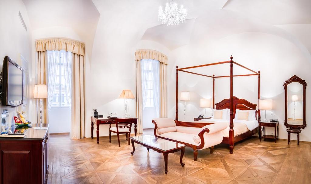 a bedroom with a large canopy bed and a chair at The Dominican in Prague