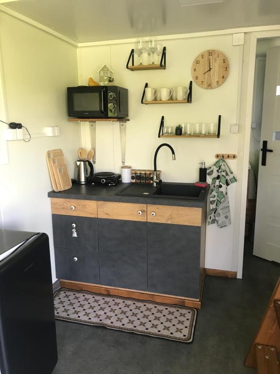 a kitchen with a sink and a clock on the wall at TinyHouses & Garden in Oravská Poruba