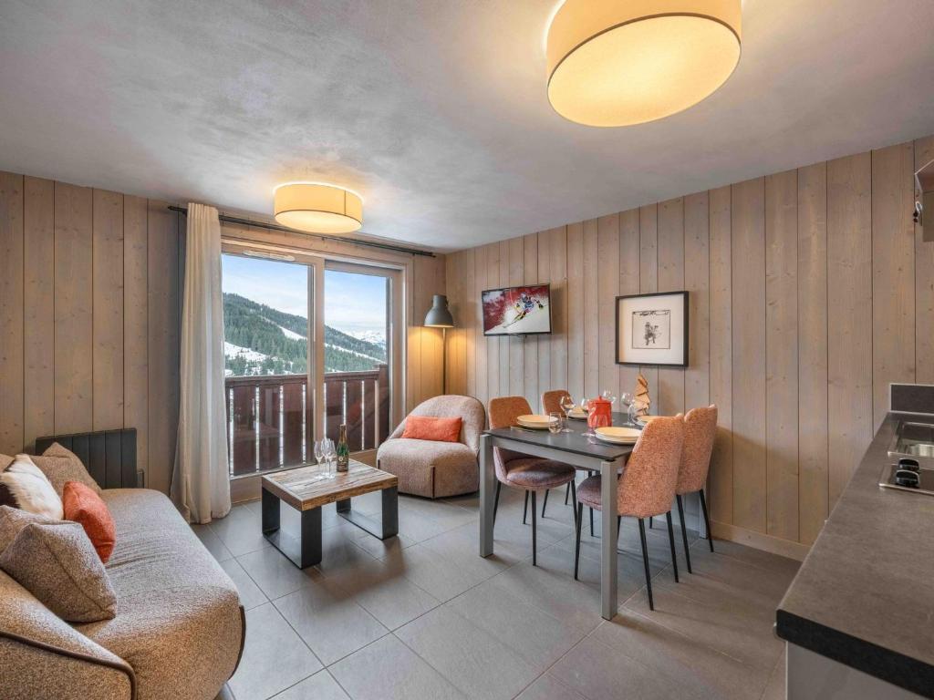 a living room with a couch and a table with chairs at Appartement Raffiné à Courchevel Moriond, 4 Étoiles, Près des Remontées Mécaniques - FR-1-563-99 in Courchevel