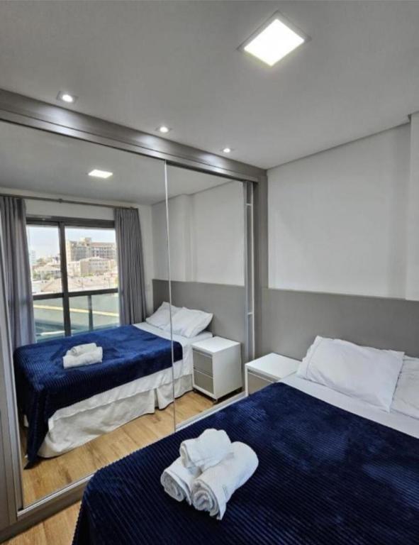 a bedroom with two beds and a mirror at Studio com Garagem e Piscina Aquecida Centro in Curitiba