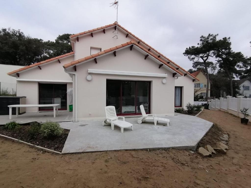 une maison blanche avec deux chaises blanches devant elle dans l'établissement Charmante maison centre, à Saint-Brévin-lʼOcéan