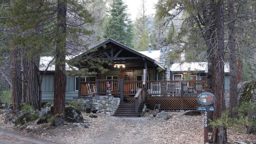 a cabin in the woods with a sign in front of it at The Little Creek Cabin in Wawona