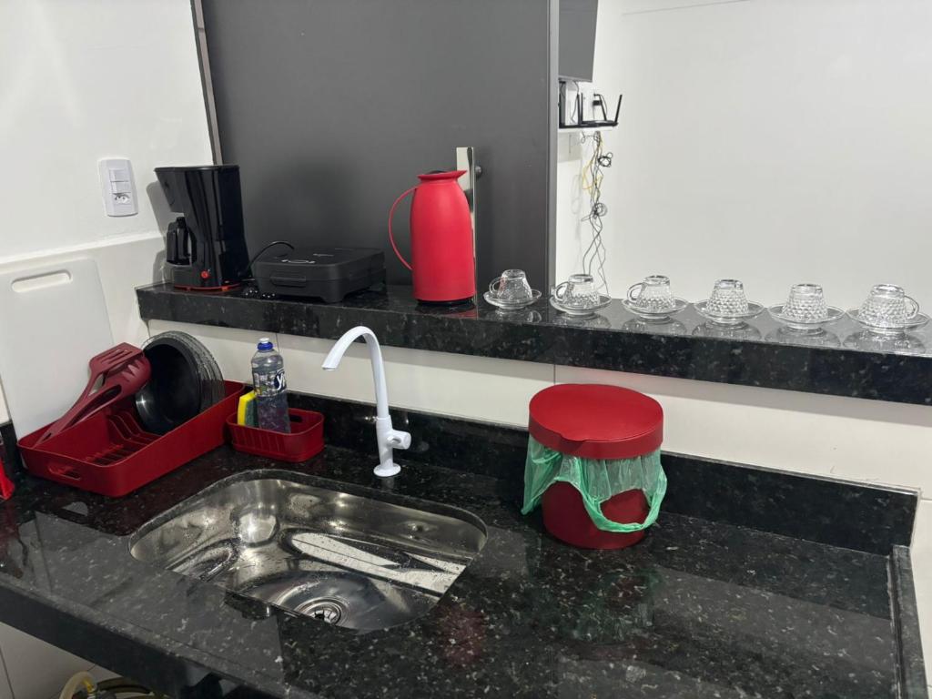 a kitchen counter with a sink and a red stool at Flats super bem localizado! in Arraial do Cabo