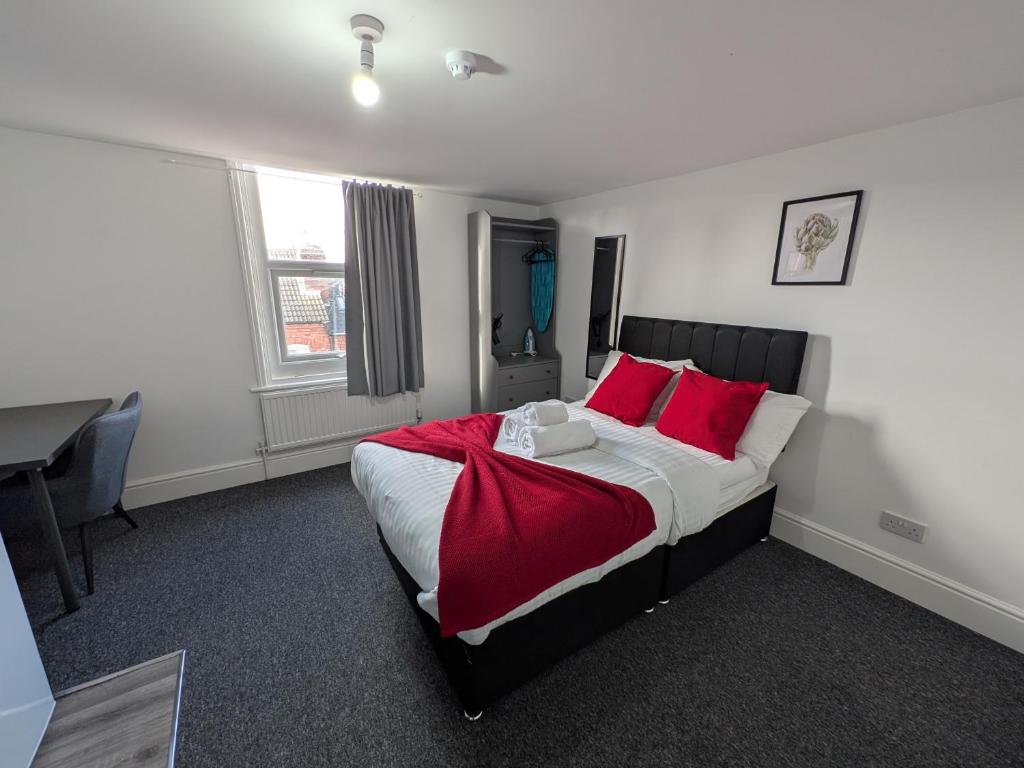 a bedroom with a bed with red pillows and a desk at Comfortable Stay - NG7 in Nottingham