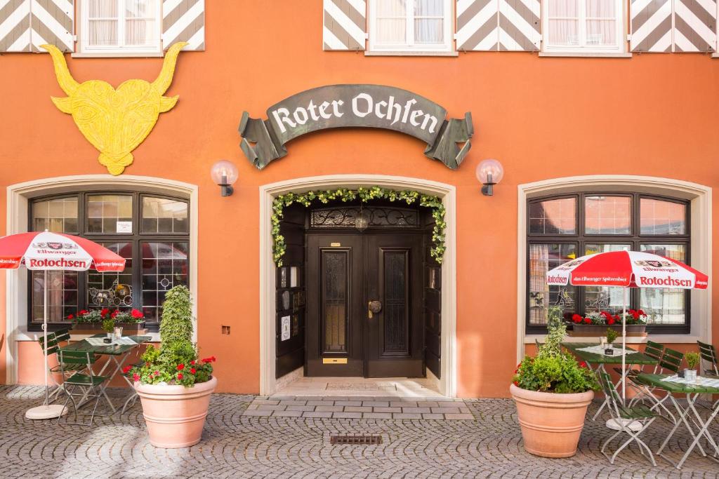 エルヴァンゲンにあるBrauereigasthof-Hotel Roter Ochsenの目の前にテーブルと椅子が並ぶオレンジ色の建物