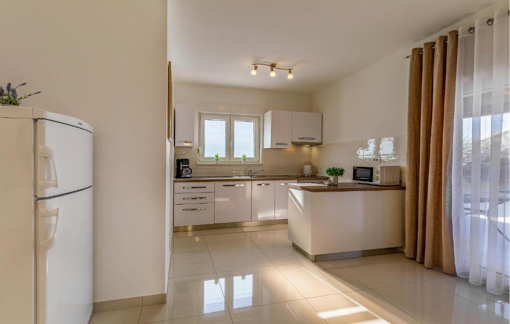 kuchnia z białymi szafkami i lodówką w obiekcie 2 Bedroom Stunning Home In Skatari w mieście Šikići