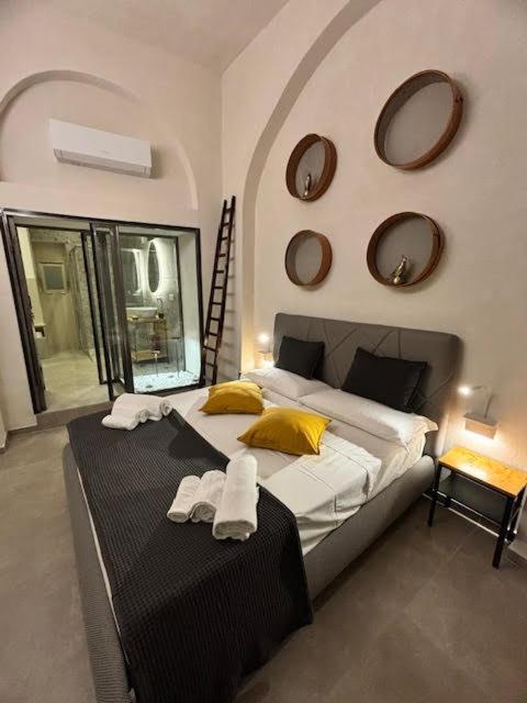 a bedroom with a bed with yellow pillows and mirrors at Casa del Pastaio in Catania