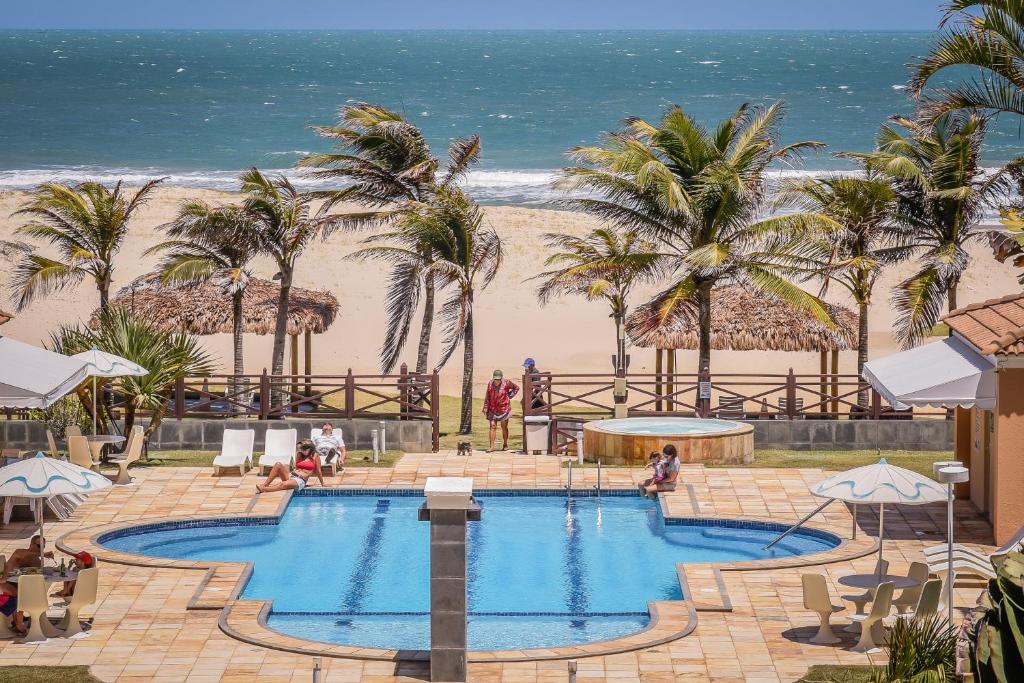 a swimming pool with the beach in the background at Atlantic Palace Apart-Hotel in Aquiraz