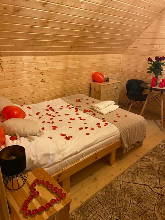 a bedroom with a bed with red rose petals on it at Bieszczadzki Amor in Zawóz