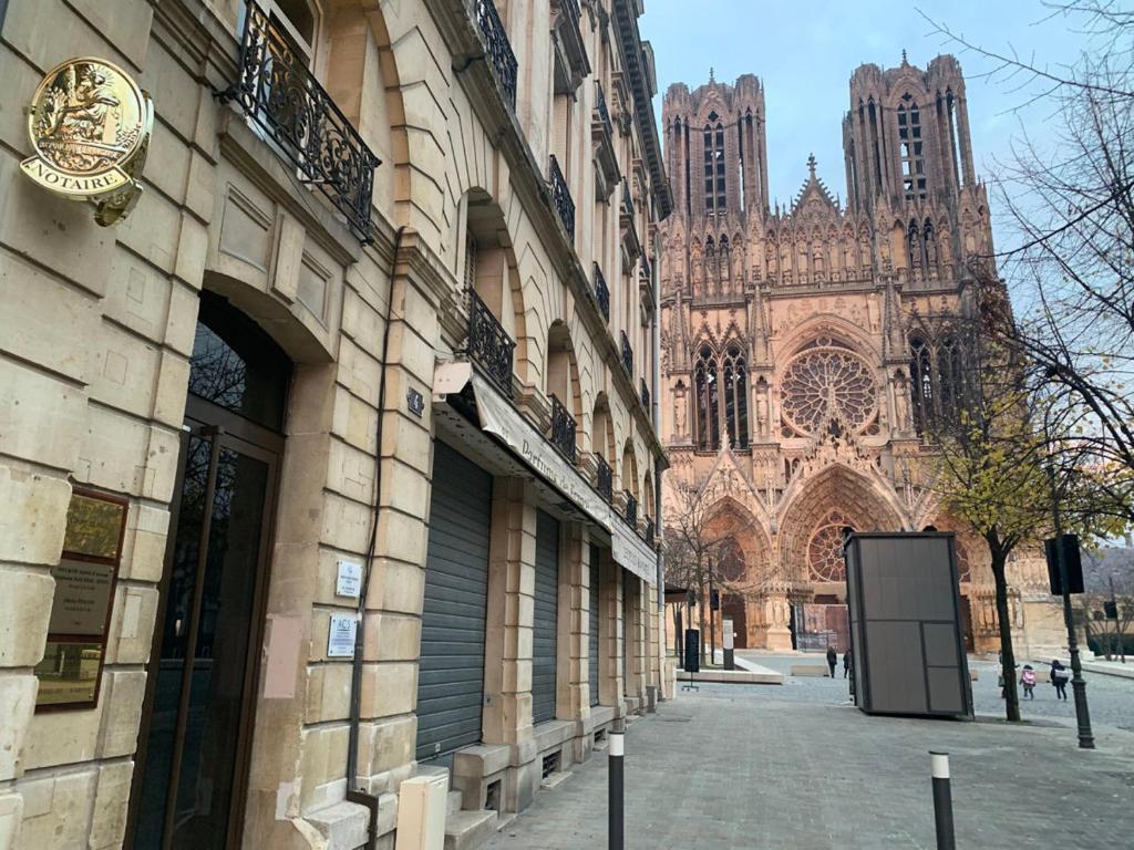un bâtiment avec une cathédrale en arrière-plan dans l'établissement Rocky #cathedraledereims, à Reims