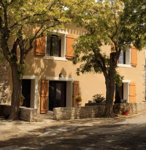 une maison avec deux arbres devant elle dans l'établissement Domaine Fontgrande Gîte, à Carcassonne