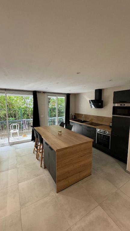 - une grande cuisine avec un îlot en bois dans l'établissement T2 neuf proche du Centre-ville, à Montpellier