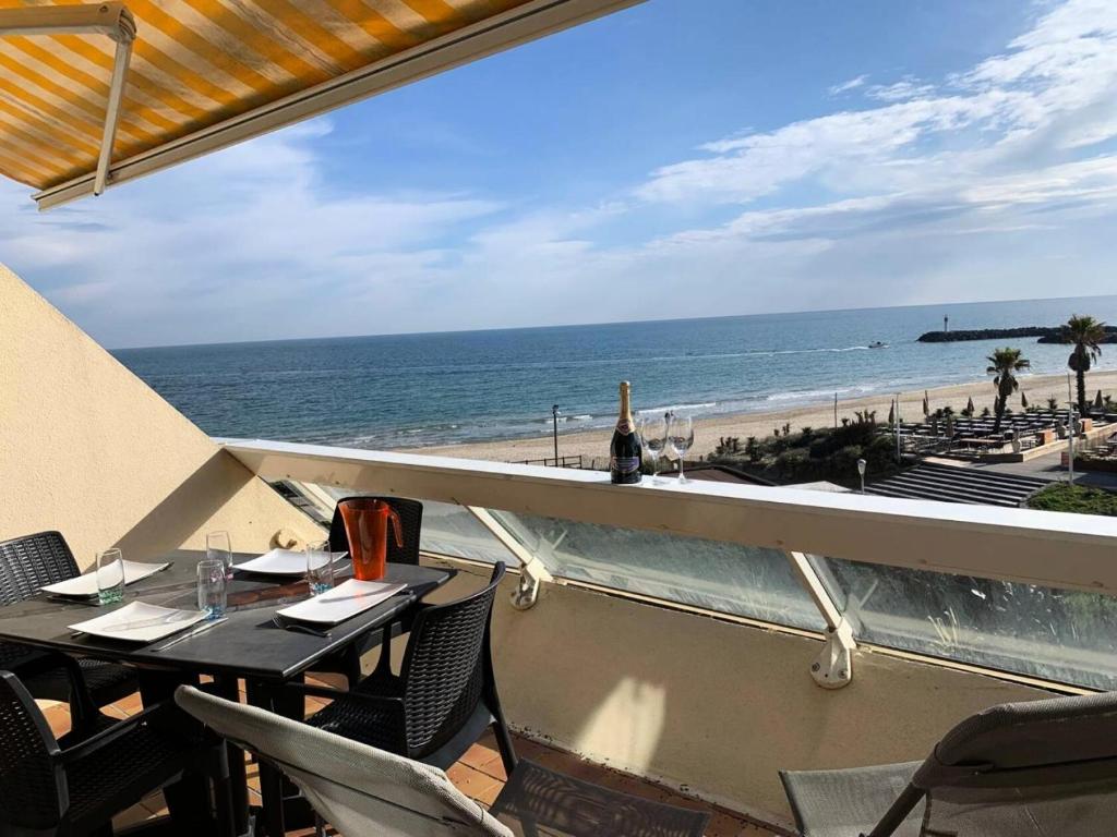 balkon ze stołem i krzesłami oraz plażą w obiekcie Résidence Héliopolis Bâtiment C - Héliopolis Bât. C studio 2 Pers. MAE-0414 w Cap d'Agde