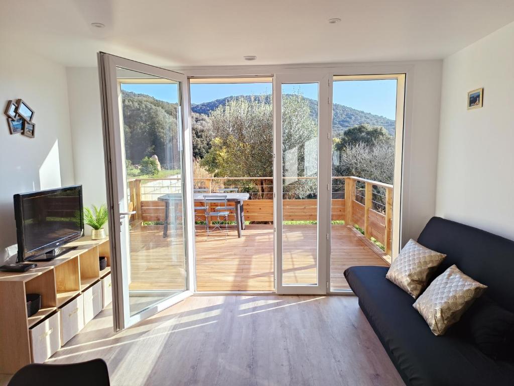 d'un salon avec une porte coulissante en verre menant à une terrasse. dans l'établissement Rez-de-jardin indépendant Ajaccio calme nature, à Ajaccio
