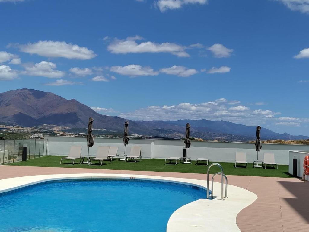 a swimming pool with chairs and a view of the mountains at Blue Sunset Retreat in Manilva