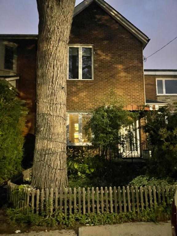 a tree in front of a house with a fence at Girls Night Out in Toronto