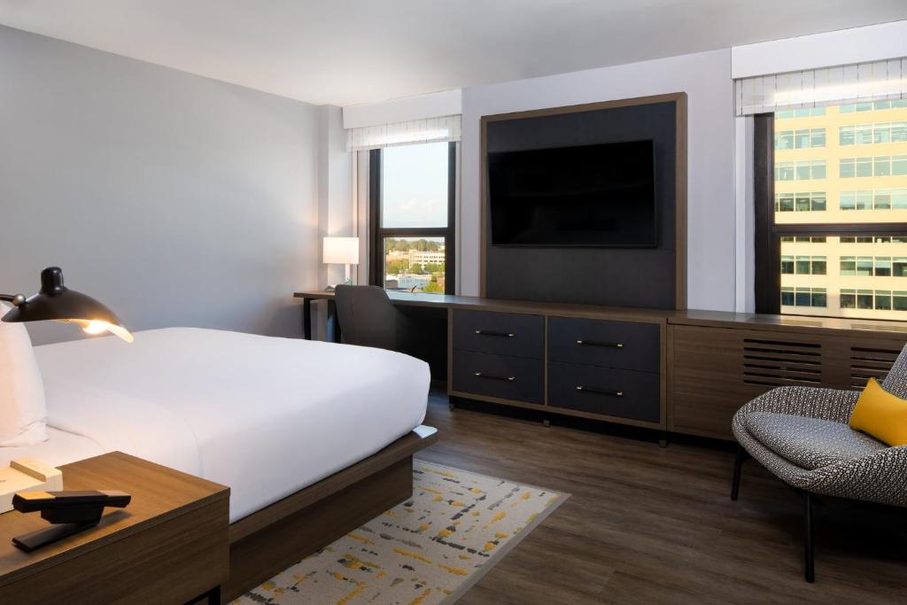 a bedroom with a bed and a television and a chair at Hotel Indigo Chattanooga - Downtown by IHG in Chattanooga