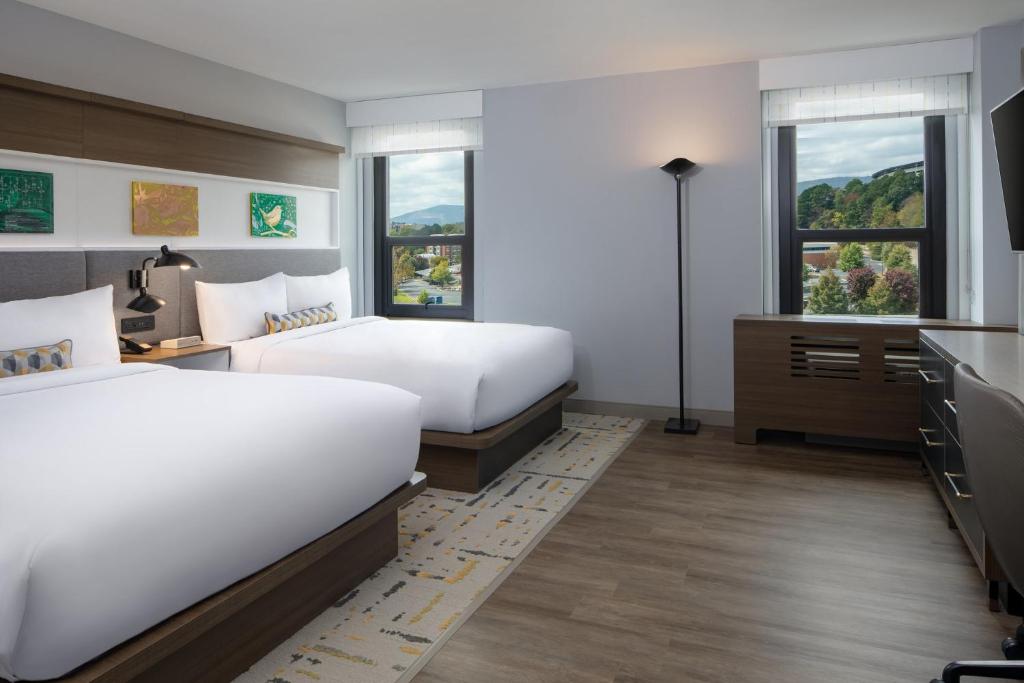 a bedroom with two beds and a desk and two windows at Hotel Indigo Chattanooga - Downtown by IHG in Chattanooga