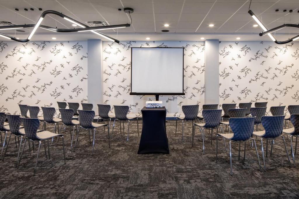 a conference room with chairs and a white screen at Hotel Indigo Chattanooga - Downtown by IHG in Chattanooga