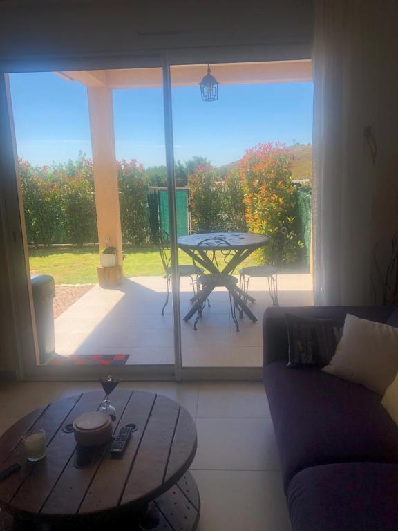 un salon avec une table et une grande fenêtre dans l'établissement Mini-villa mitoyenne de type F2 proche Golfe de Lava, à Appietto