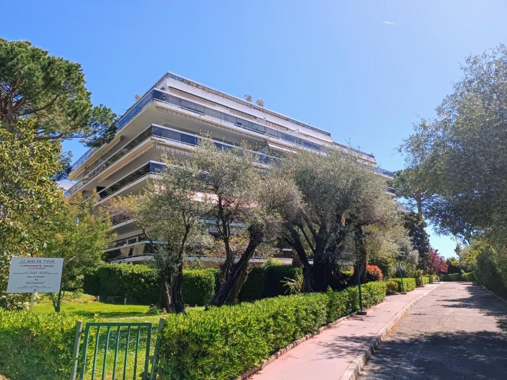 un grand bâtiment avec des arbres devant un trottoir dans l'établissement ARA 40m2 Classé Immense Terrasse 35 m2 Piscine Antibes Juan Parking, à Antibes