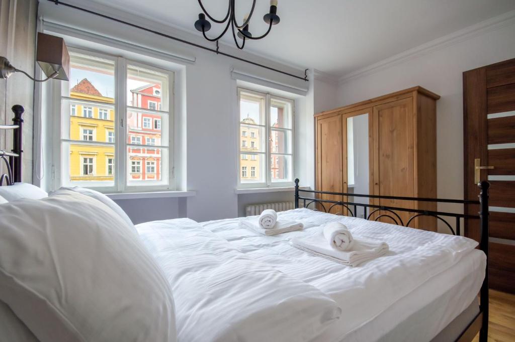a bedroom with a white bed with two towels on it at Perła Rynku - urokliwy apartament w samym centrum in Wrocław