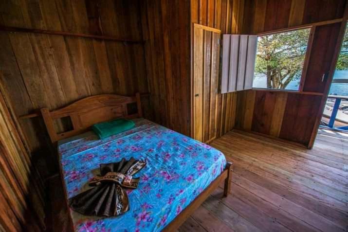 een slaapkamer met een bed in een houten kamer bij Santa Helena do inglês in Iranduba