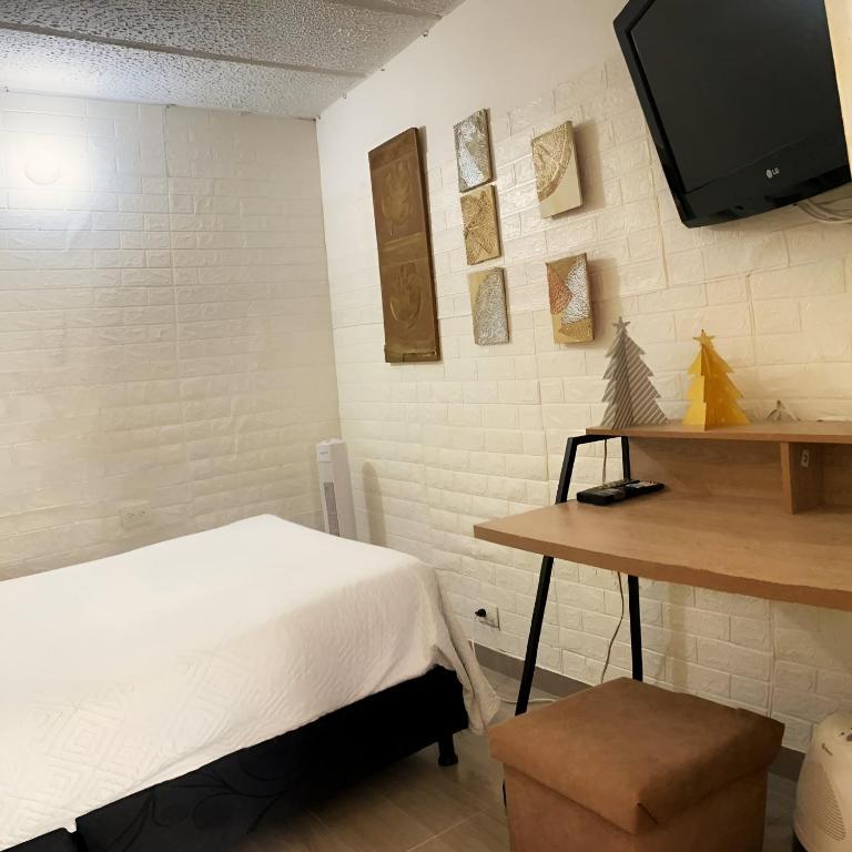 a bedroom with a bed and a table and a tv at BORA - Apto 101Tu espacio fuera de casa in Ibagué