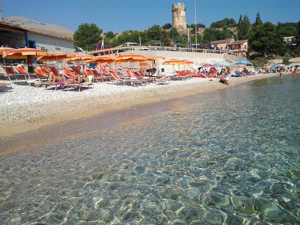 カステッランマーレ・デル・ゴルフォにあるCasa Vacanze Al Ma Giの椅子と水中の人々が泳ぐビーチ