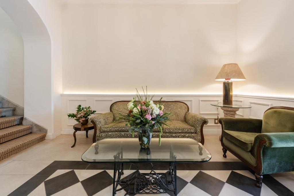 a living room with two couches and a table with a vase of flowers at Villa Ganz Boutique Hotel in Guadalajara