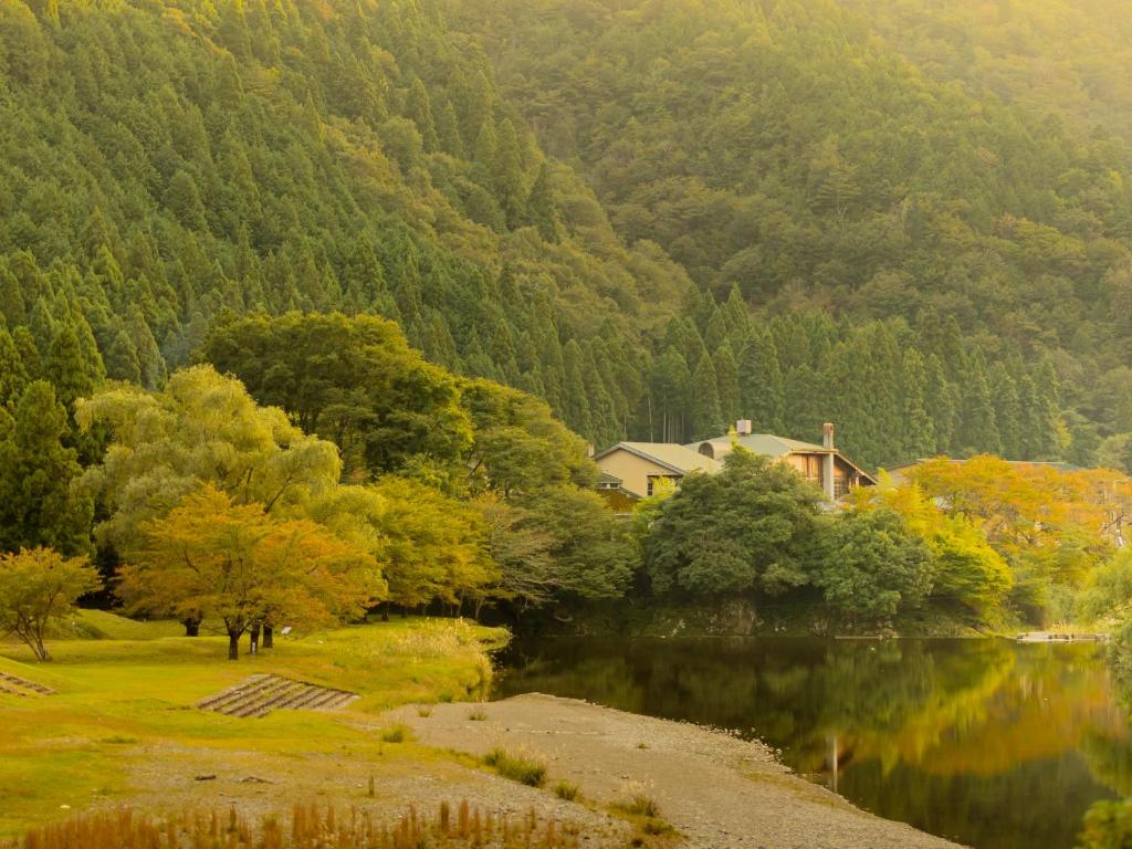 a house on the shore of a lake with trees at Miyama Nature and Culture Village Kajikaso in Nakamura