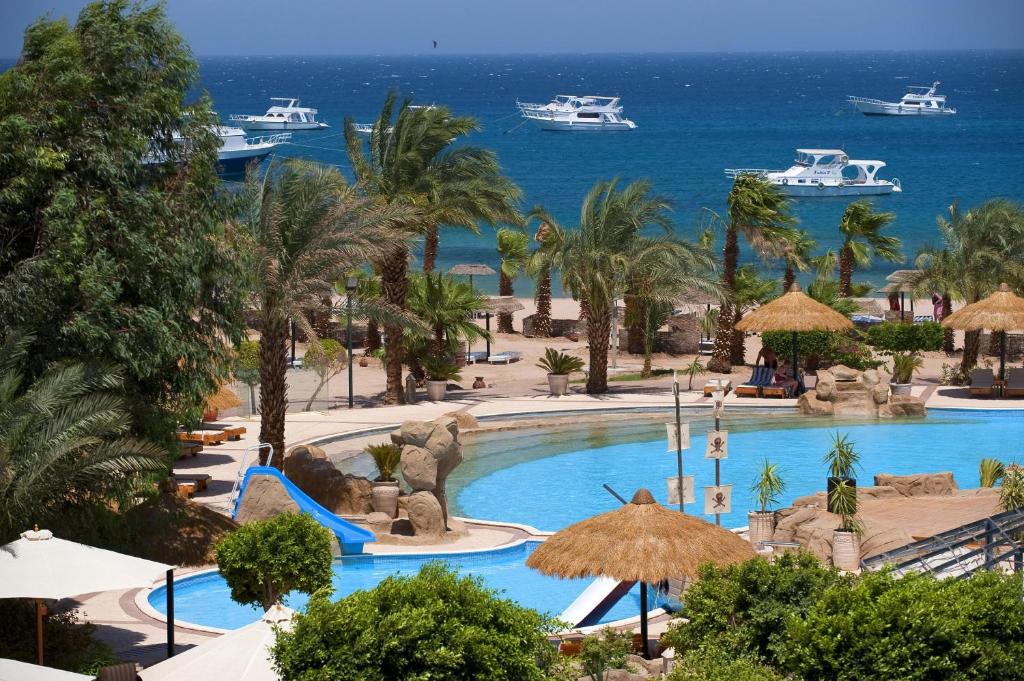 a view of a resort pool with boats in the water at Lotus Bay Resort in Hurghada