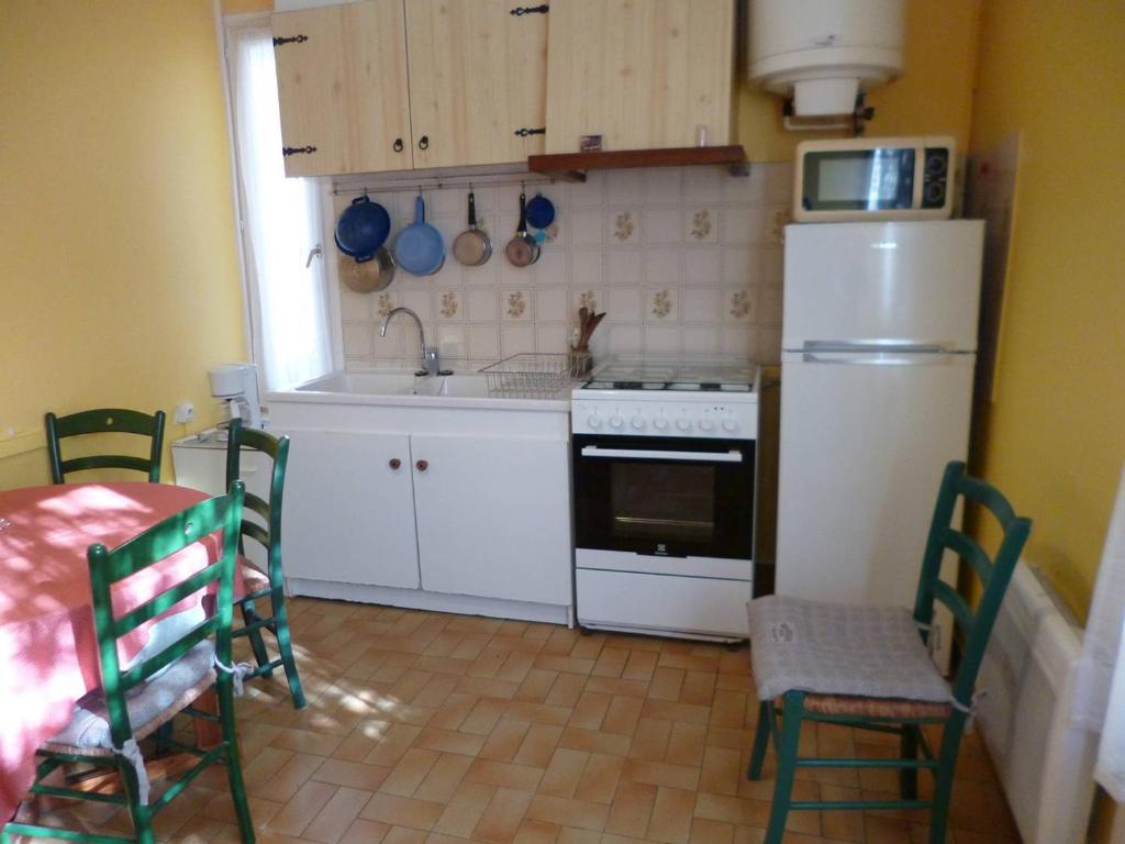 Il comprend une cuisine équipée d'un réfrigérateur blanc, d'une table et de chaises. dans l'établissement T3 cosy avec parking près du centre - FR-1-571-67, à Balaruc-les-Bains
