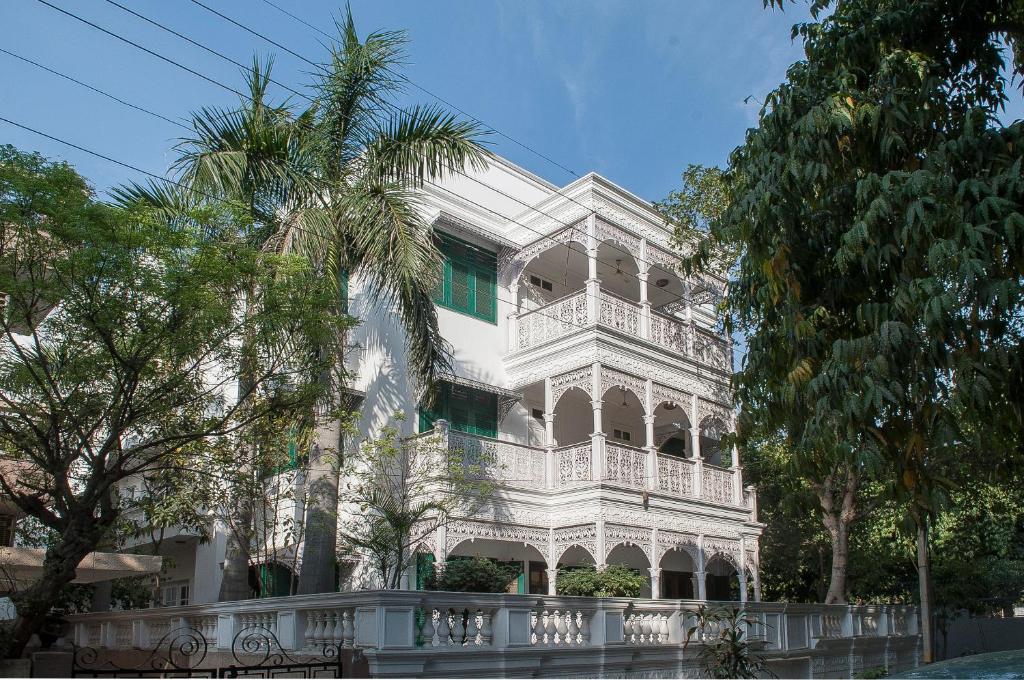 un bâtiment blanc avec un palmier en face dans l'établissement Villa 33, à New Delhi