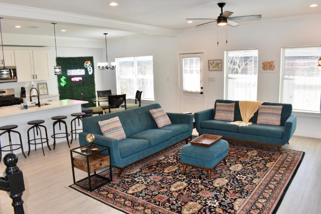 a living room with two blue couches and a kitchen at 4-Bed Home, Prime Houston Location in Houston