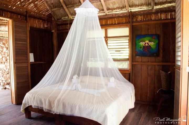 a bed with a mosquito net in a room at Villas Eco-Románticas Kúuch Ka´anil in Bacalar