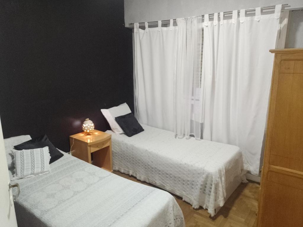 two beds in a room with white curtains at Departamento 3am centro in Mar del Plata
