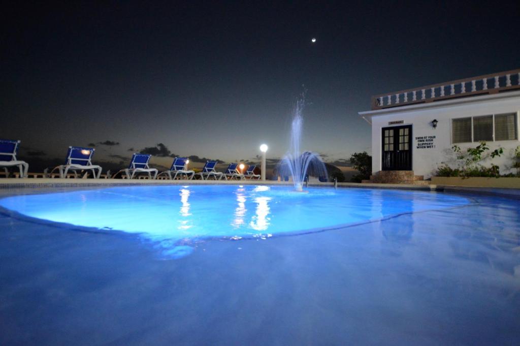 fontanna w środku basenu w nocy w obiekcie Beyond Sunset Resort & Villas w mieście Treasure Beach