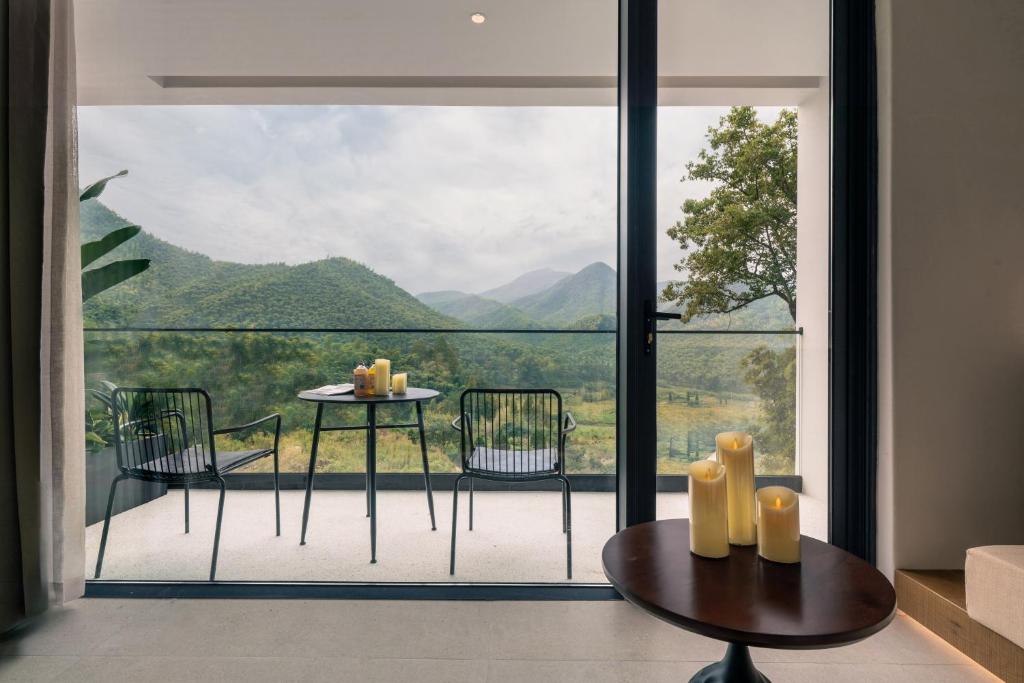 a room with a balcony with a table and chairs at Wild Persimmon Manor Cove Mist Healing Hot Spring in Anji
