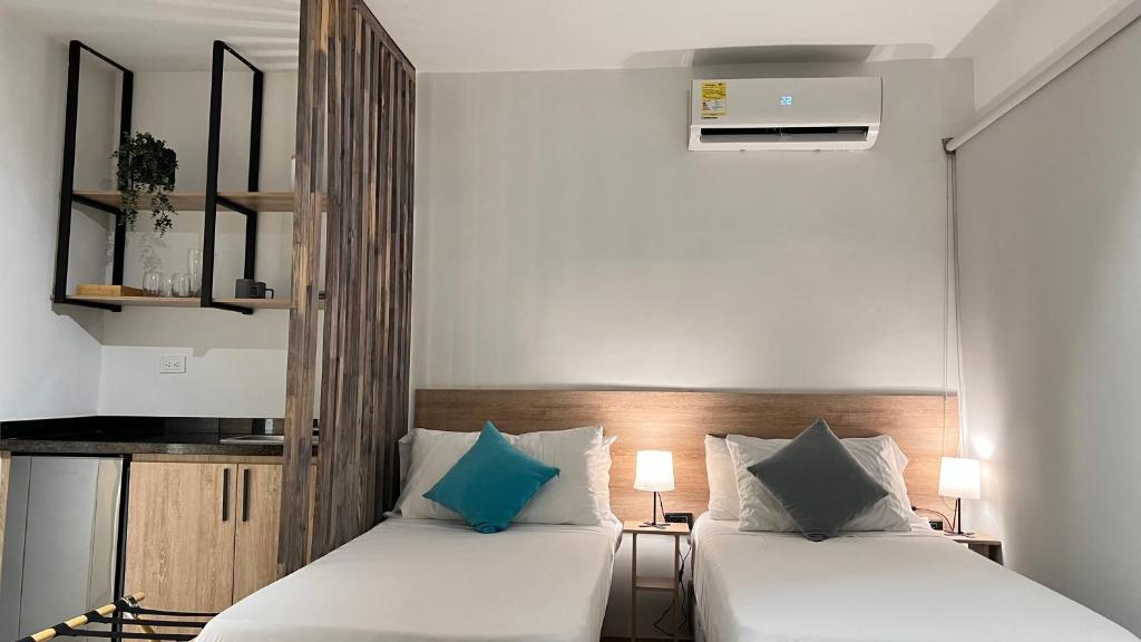 two beds in a small room with white and blue pillows at HOTEL 9.5 SAN FERNANDO in Cali