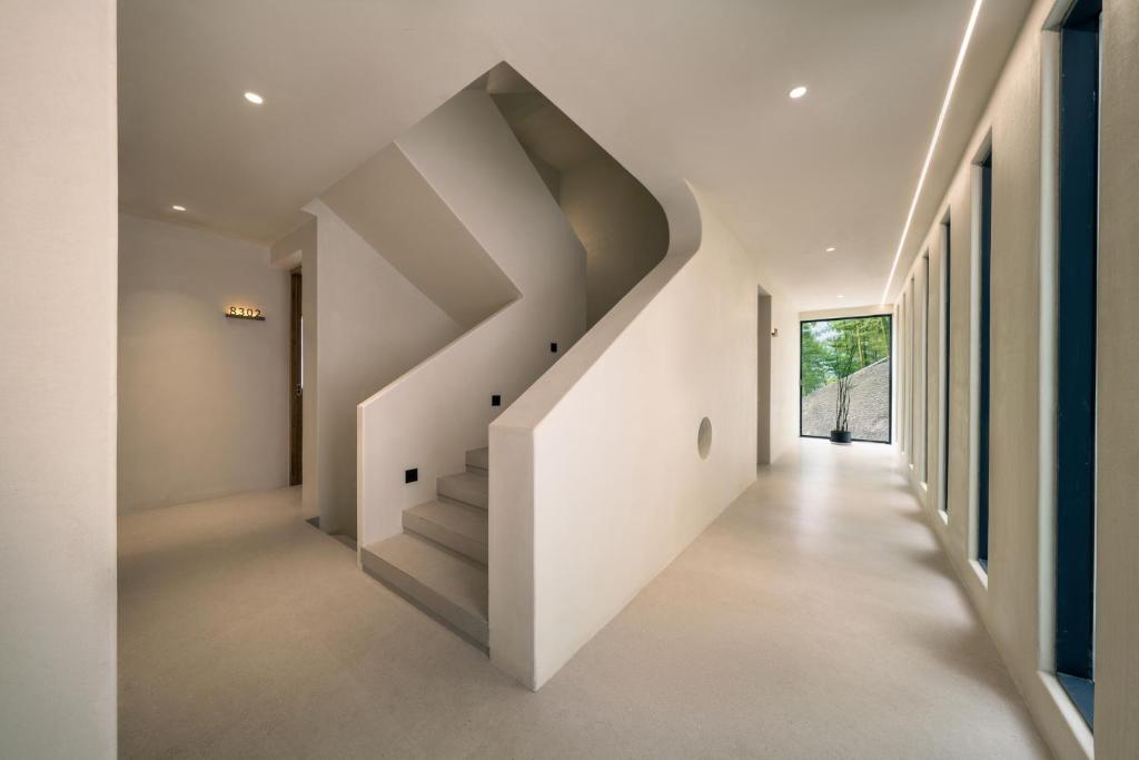 a white hallway with stairs in a house at Wild Persimmon Manor Cove Mist Healing Hot Spring in Anji