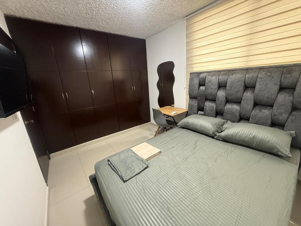 a bedroom with a large bed with a padded headboard at Hermosa habitación a una cuadra del Ventura plaza 2 in Cúcuta
