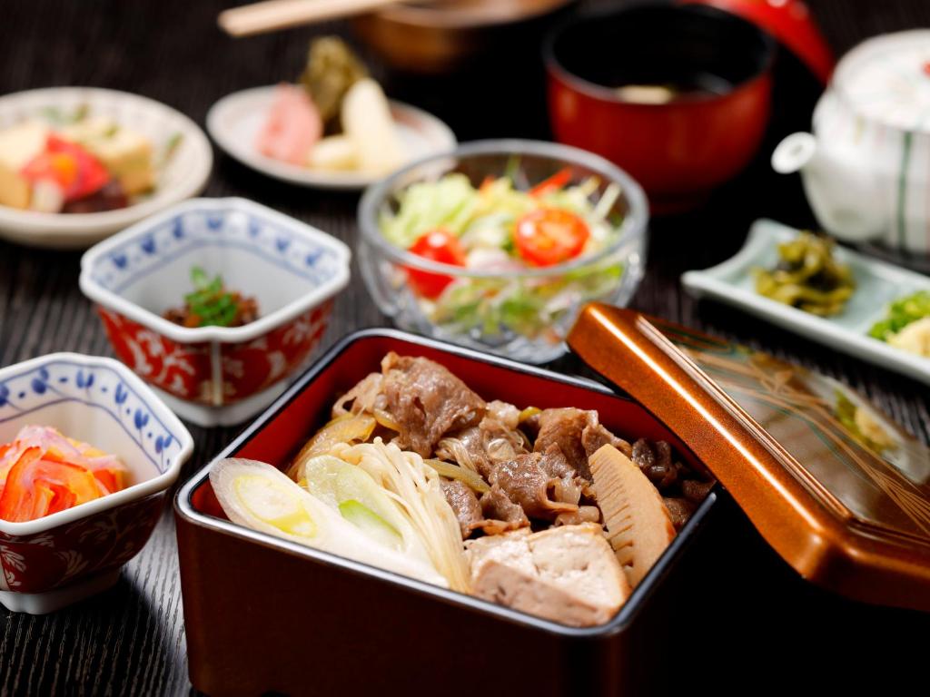 a table topped with bowls of food and vegetables at Kanazawa Hakuchoro Hotel Sanraku -Natural Hot Spring- in Kanazawa