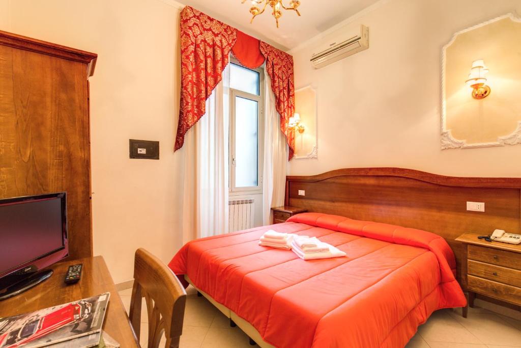 sypialnia z łóżkiem, biurkiem i telewizorem w obiekcie Cambridge Hotel w Rzymie
